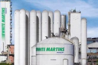 Fábrica da White Martins com tanques e torres brancas, representando indústria de gases.