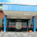 Fachada da delegacia de homicídios com a inscrição 'Homicídios' e brasão da Polícia Civil.