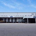 Fachada da empresa Zilla com céu azul e rampas de carregamento.