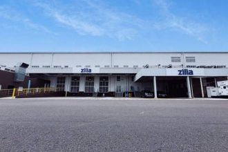 Fachada da empresa Zilla com céu azul e rampas de carregamento.