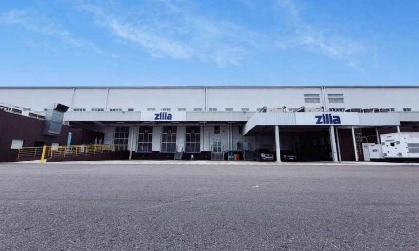 Fachada da empresa Zilla com céu azul e rampas de carregamento.