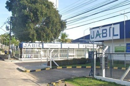 Fachada da fábrica da Jabil em Manaus, com o letreiro 'JABIL' em destaque e uma entrada com portão.