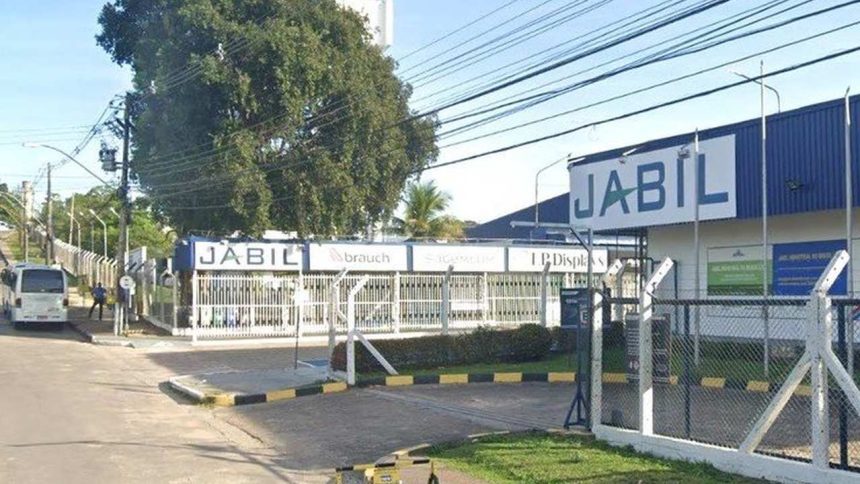 Fachada da fábrica da Jabil em Manaus, com o letreiro 'JABIL' em destaque e uma entrada com portão.