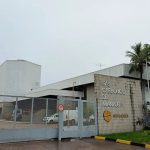 Fachada da fábrica de gases industriais Gas Carbonico de Manaus, do Grupo Simões, com portão e palmeiras.