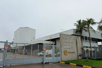 Fachada da fábrica de gases industriais Gas Carbonico de Manaus, do Grupo Simões, com portão e palmeiras.
