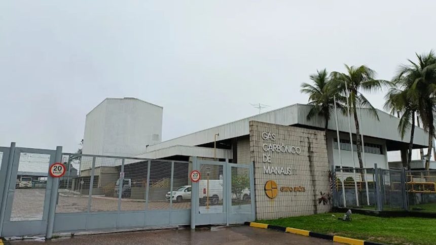 Fachada da fábrica de gases industriais Gas Carbonico de Manaus, do Grupo Simões, com portão e palmeiras.