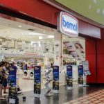 Fachada da loja Bemol em shopping center, com pessoas e banners de anúncios.