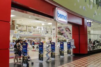 Fachada da loja Bemol em shopping center, com pessoas e banners de anúncios.