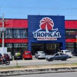 Fachada da loja Tropical Multiloja em Manaus, com carros estacionados.