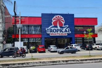 Fachada da loja Tropical Multiloja em Manaus, com carros estacionados.