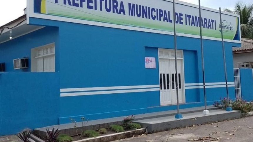 Fachada da Prefeitura Municipal de Itamarati, em tom azul, com placa e mastros.