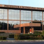 Fachada da Prefeitura Municipal de Manaus, com arquitetura moderna e vegetação.