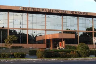 Fachada da Prefeitura Municipal de Manaus, com arquitetura moderna e vegetação.