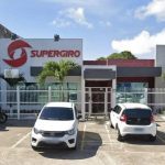 Fachada da Supergiro, distribuidora em Manaus, com carros estacionados e letreiro.