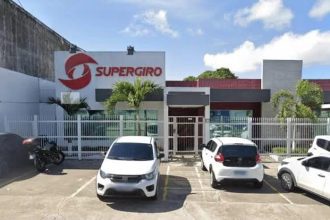 Fachada da Supergiro, distribuidora em Manaus, com carros estacionados e letreiro.