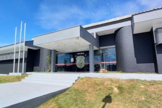 Fachada de delegacia de polícia civil em dia ensolarado.