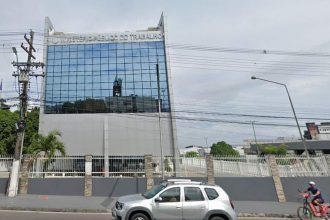 Fachada do Ministério Público do Trabalho, com carro e ciclista na frente.