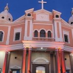 Fachada do Santuário de São José Operário com iluminação noturna, em tons de rosa e branco.