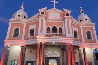 Fachada do Santuário de São José Operário com iluminação noturna, em tons de rosa e branco.