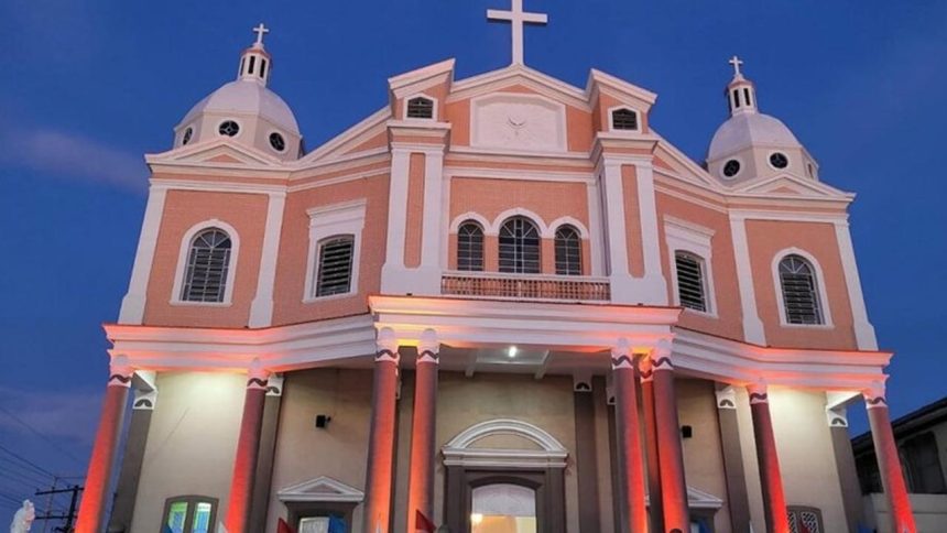 Fachada do Santuário de São José Operário com iluminação noturna, em tons de rosa e branco.