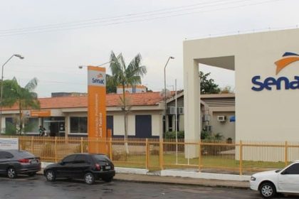 Fachada do Senac em Manaus, com carros estacionados e placa indicativa.