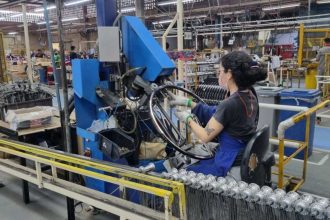 Funcionária da Caloi trabalha em linha de produção em Manaus, montando aros de bicicleta.