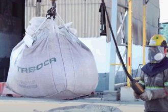 Funcionário da Mineração Taboca em Presidente Figueiredo com equipamento de proteção e saco de material sendo içado.