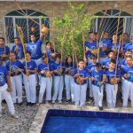 Grupo de capoeiristas em evento gratuito em Manaus, segurando berimbaus e vestindo azul e branco.