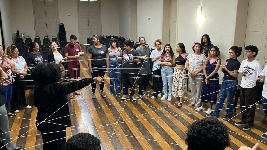 Grupo de pessoas em círculo em um workshop, com fios de barbante conectados.