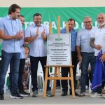 Grupo de pessoas em evento de inauguração, com placa de 'Pavimentação do Sistema Viário de Itacoatiara'.