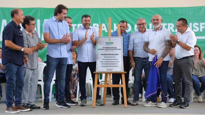 Grupo de pessoas em evento de inauguração, com placa de 'Pavimentação do Sistema Viário de Itacoatiara'.