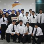 Grupo de pessoas em uniforme de garçom em frente ao logotipo da Senac