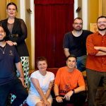 Grupo de pessoas posando para foto em frente a um teatro.