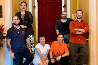 Grupo de pessoas posando para foto em frente a um teatro.