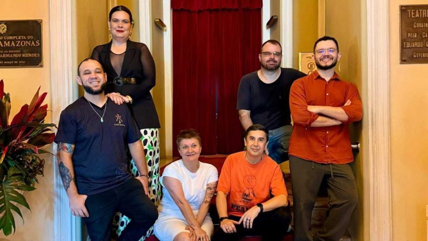 Grupo de pessoas posando para foto em frente a um teatro.