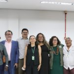 Grupo de pessoas sorrindo entre eles pessoas de uma comunidade quilombola em uma reunião.