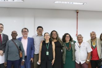 Grupo de pessoas sorrindo entre eles pessoas de uma comunidade quilombola em uma reunião.
