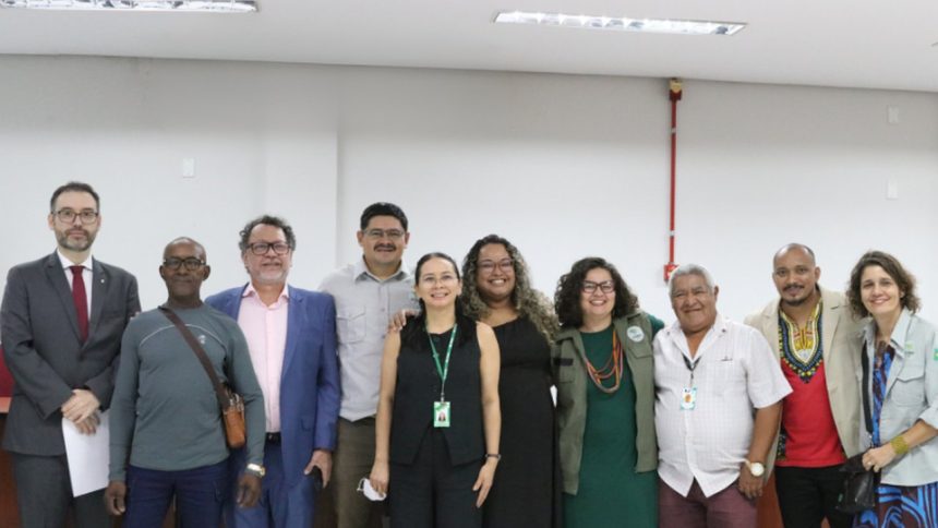 Grupo de pessoas sorrindo entre eles pessoas de uma comunidade quilombola em uma reunião.