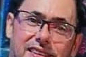 Homem de óculos escuros, suspeito de tráfico de drogas, procurado pela polícia.