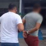 Homem é preso por estupro de vulnerável. Policial conduz suspeito algemado.