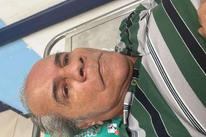 Homem idoso aguardando em hospital, usando camisa listrada