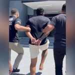 Homem preso sendo escoltado por policiais civis em frente a delegacia