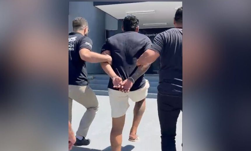 Homem preso sendo escoltado por policiais civis em frente a delegacia