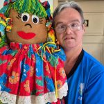 Homem segura boneca de pano colorida em evento da APAE em Manaus