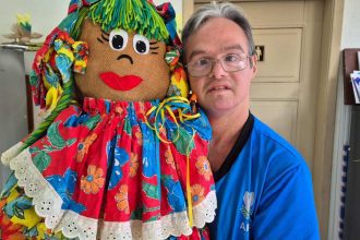 Homem segura boneca de pano colorida em evento da APAE em Manaus