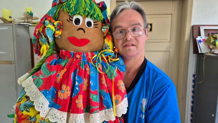Homem segura boneca de pano colorida em evento da APAE em Manaus