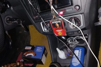 Interior de carro com chave na ignição, crachá com foto e outros objetos.