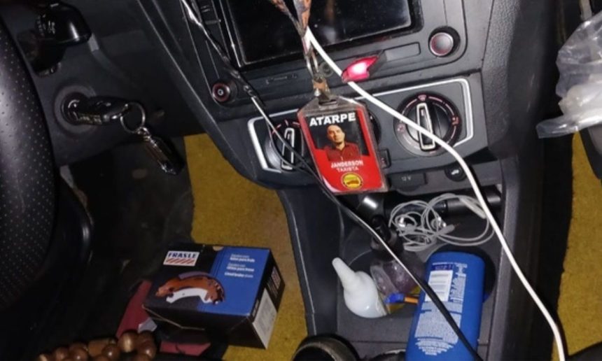 Interior de carro com chave na ignição, crachá com foto e outros objetos.