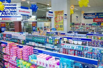 Interior de farmácia Pague Menos em Manaus, com prateleiras de produtos e banners promocionais.
