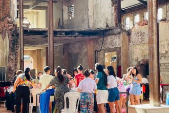 Interior de prédio antigo com pessoas em evento, possivelmente mercado. Destaca-se oficina e aula de ritmos.